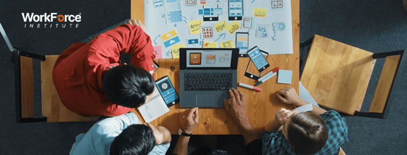 Team collaborating on digital marketing project with laptop, charts, and mobile app designs at WorkForce Institute.